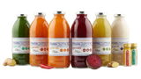 Presscription juice cleanse: a row of cold-pressed juices and wellness shots in glass bottles with beetroot, ginger and fresh produce