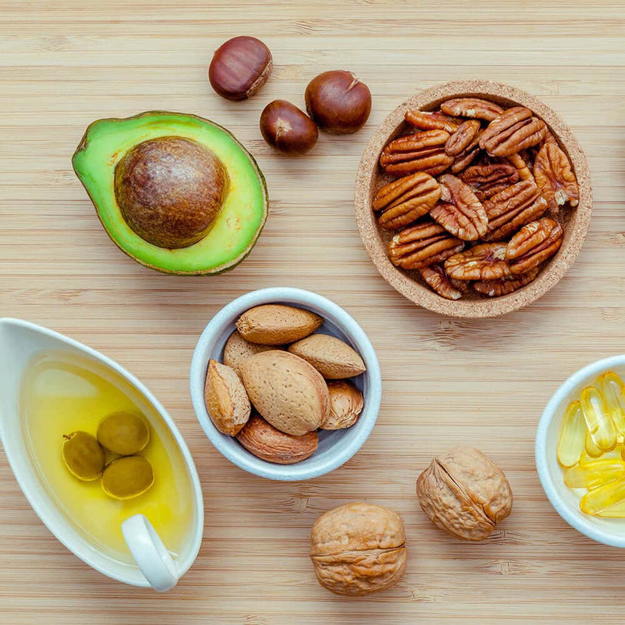 Avocado, nuts, olive oil and capsules on a wooden board