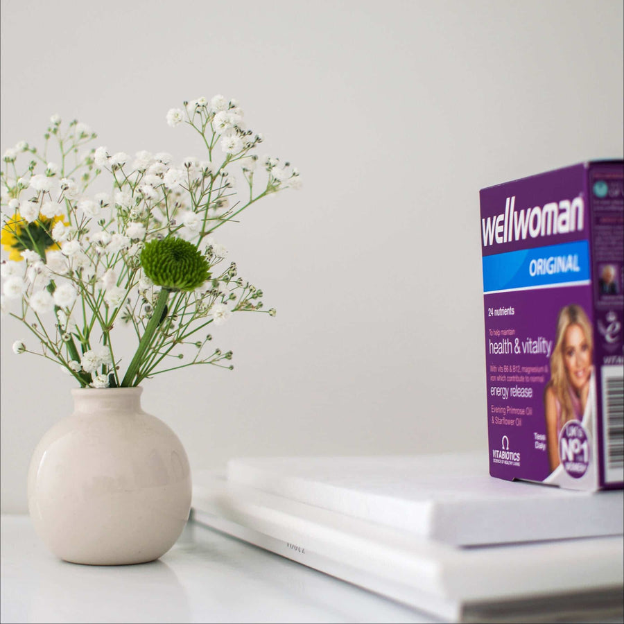 Box of supplements next to a vase of flowers