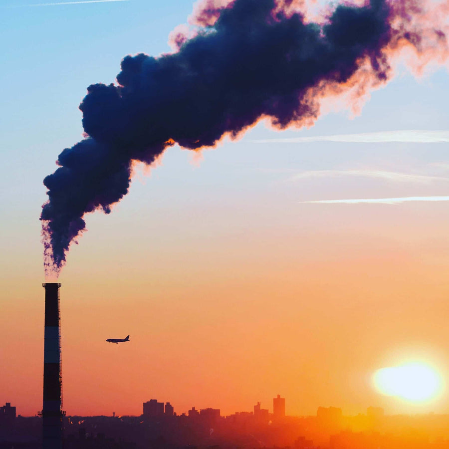 Factory chimney smoke against a sunset sky