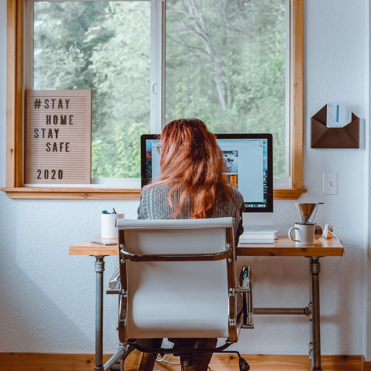 Woman working at a home desk by a window