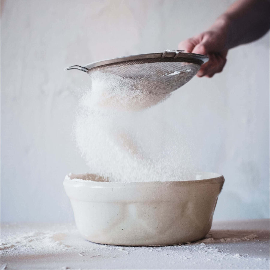 Sieving white powder into a bowl
