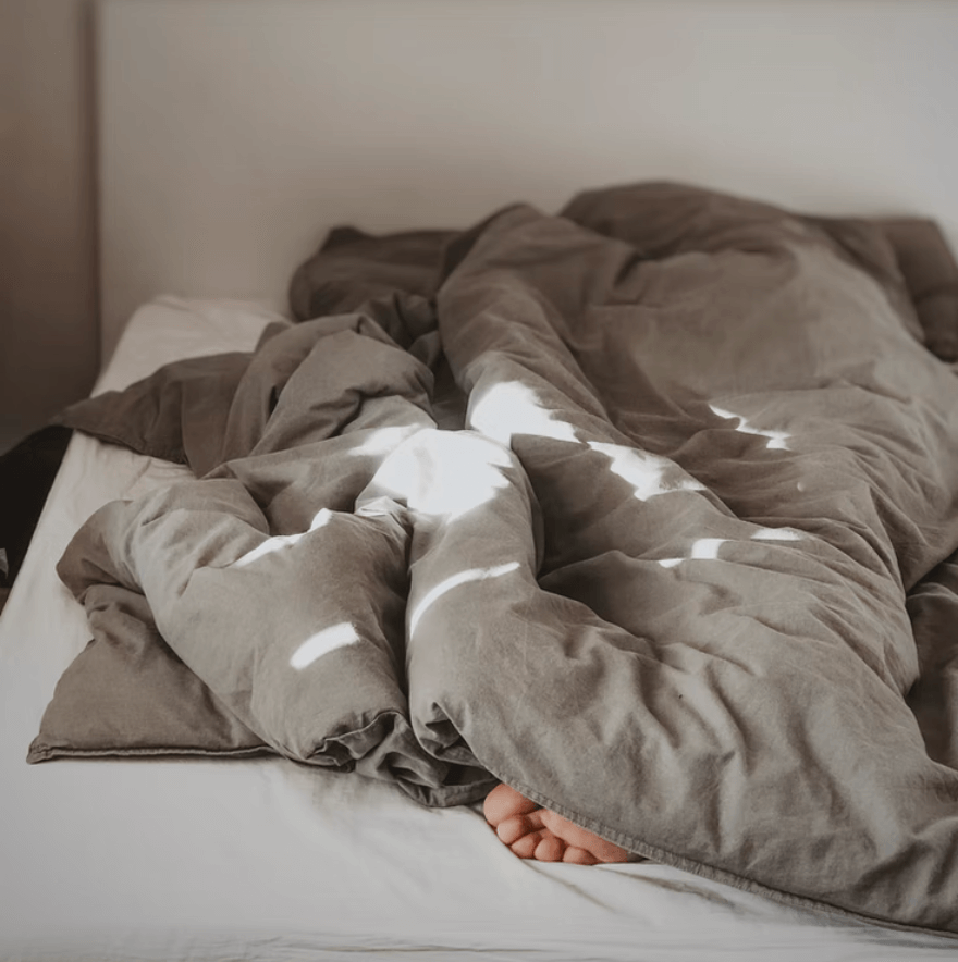 Unmade bed with a grey duvet