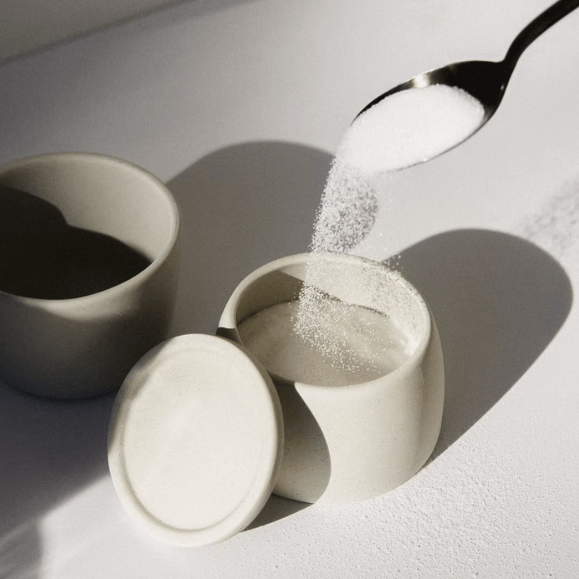 Sugar being spooned into a white pot