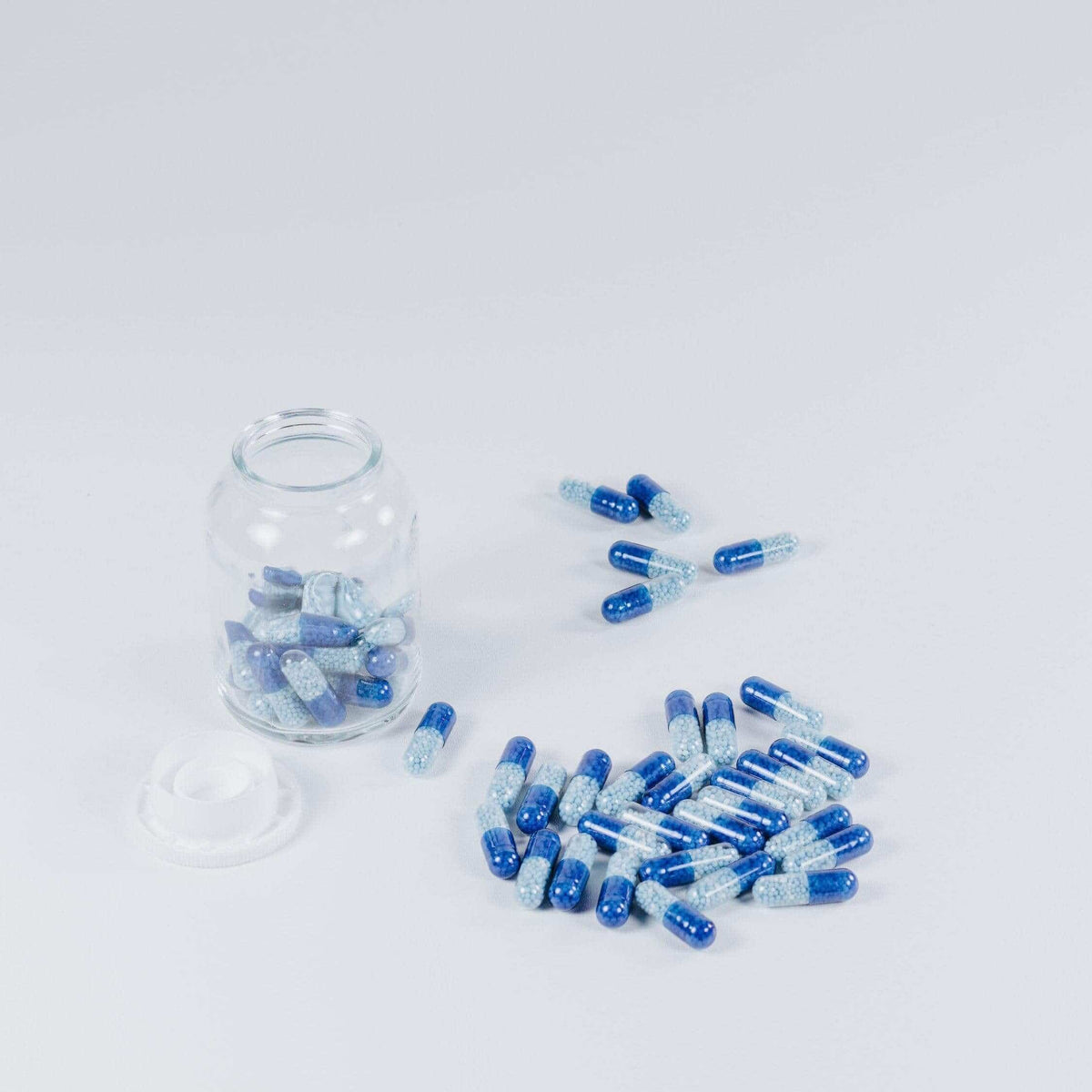Glass jar and spilled blue capsules
