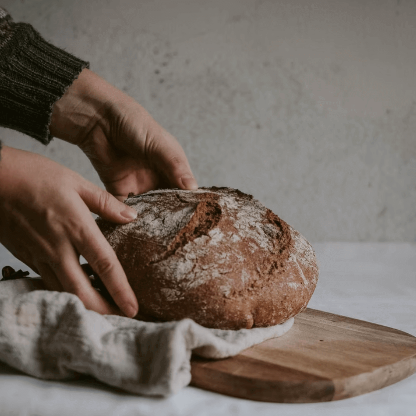Hands holding a loaf of sourdough bread