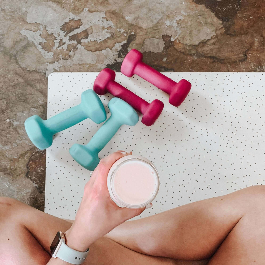 Dumbbells and a glass of milk on an exercise mat