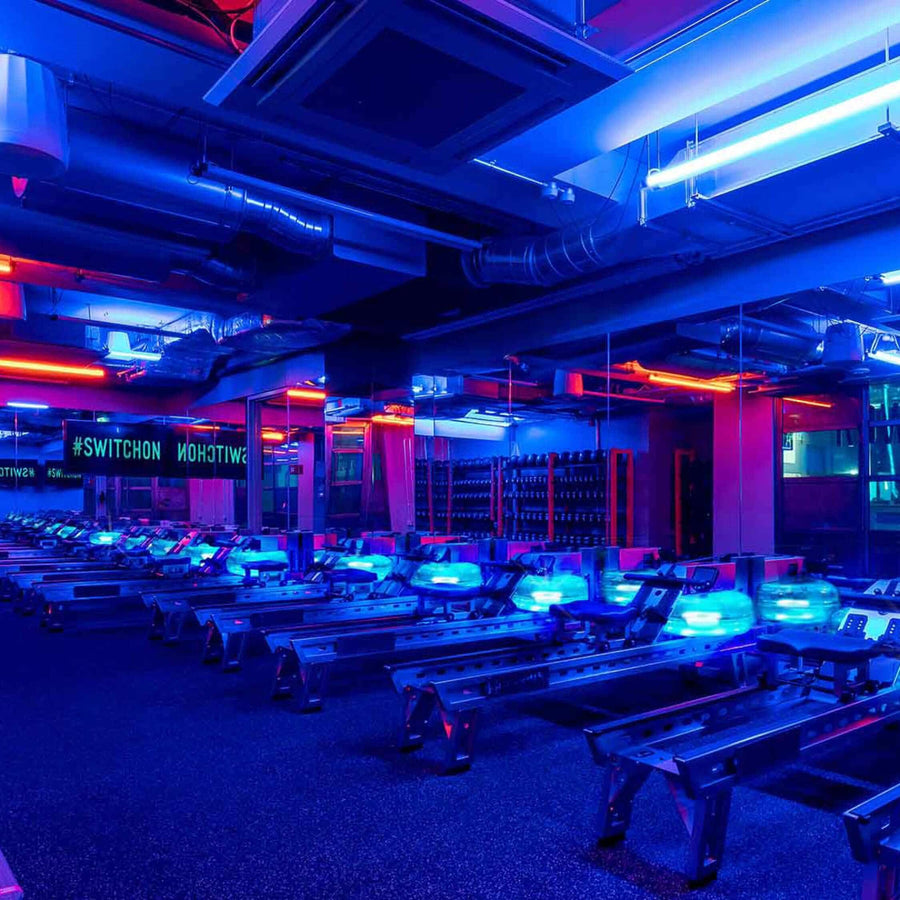 Indoor rowing machines in a blue-lit gym