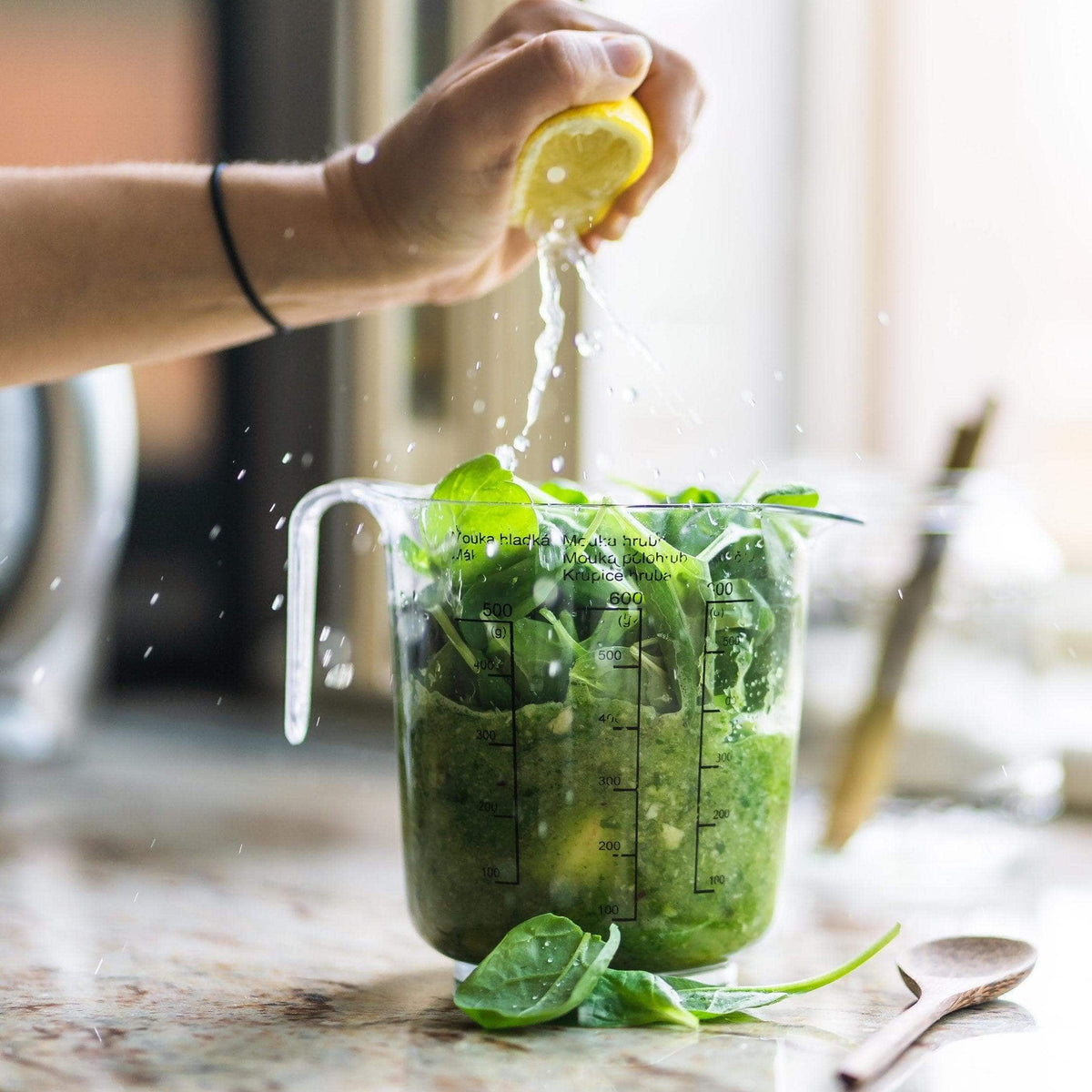 Squeezing lemon into a jug of green leaves