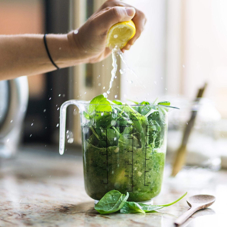 Squeezing lemon into a jug of green leaves