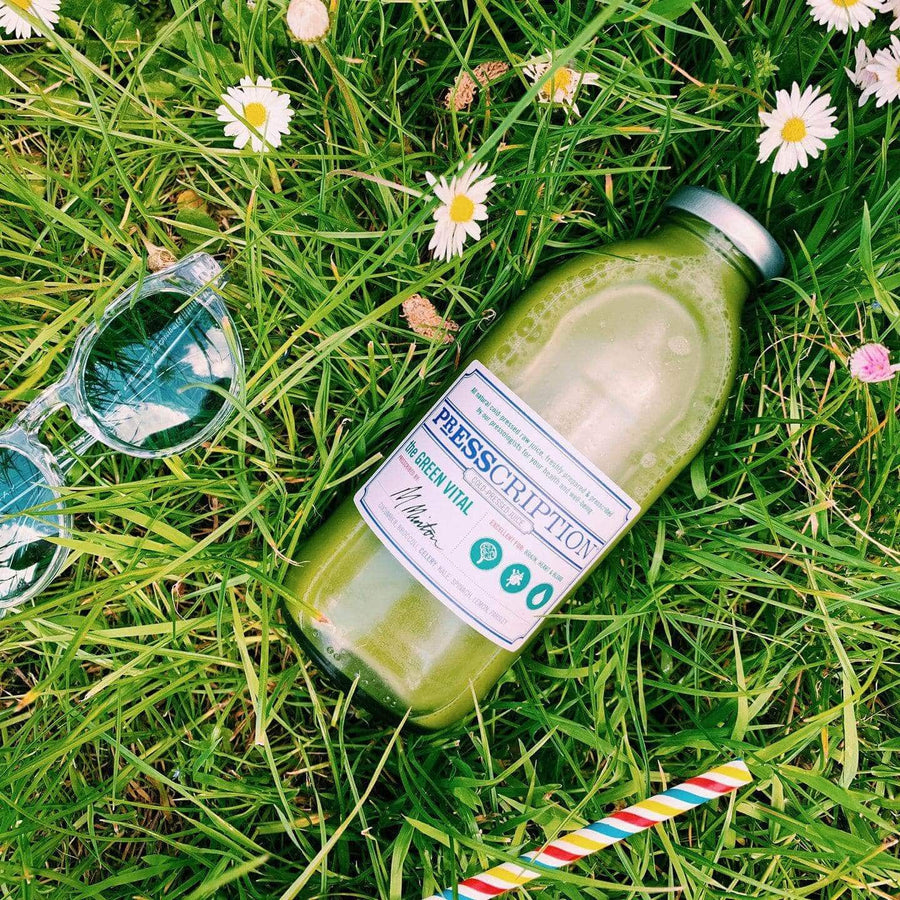 Bottle of Presscription green juice lying in the grass with daisies