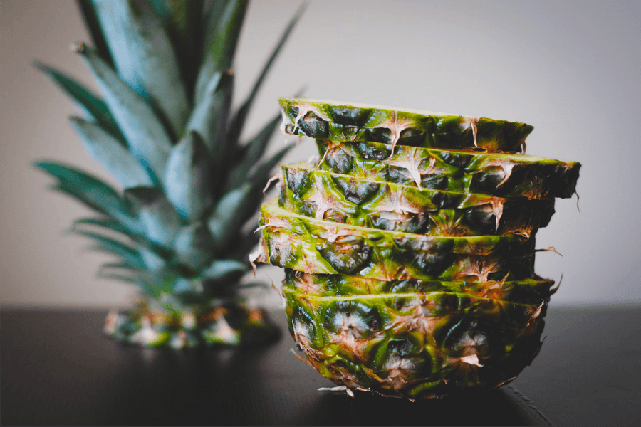 Sliced pineapple stacked on a dark table